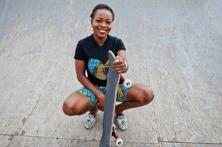 Young african american woman posed with skateboard in skate park.の写真素材