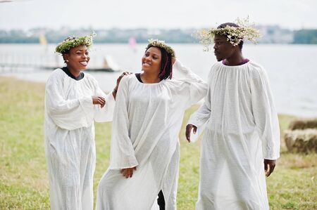 Three african american friends on white cloaks and wreath having fun together.