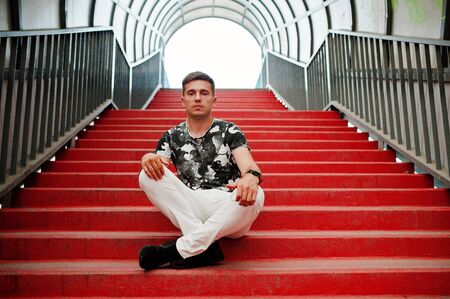 Lifestyle portrait of handsome man posing in red stairs of the city tunnel.