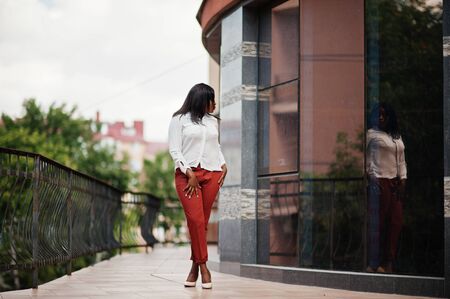 Formally dressed african american business woman in white blouse and red trousers. Successful dark skinned businesswoman.の写真素材