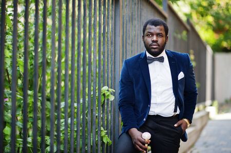 Handsome fashionable african american man in formal wear and bow tie with walking stick.の写真素材