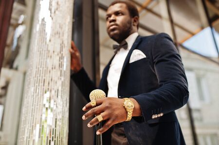 Handsome fashionable african american man in formal wear and bow tie with walking stick.