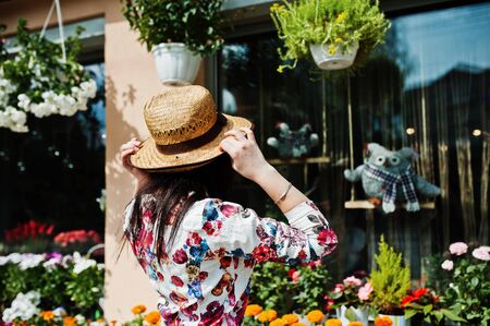 Summer portrait of brunette girl in pink glasses and hat against flowers shop.の写真素材