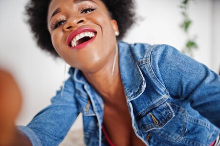 Close up portrait of an attractive african american woman with afro hair wear jeans jacket, posed at...
