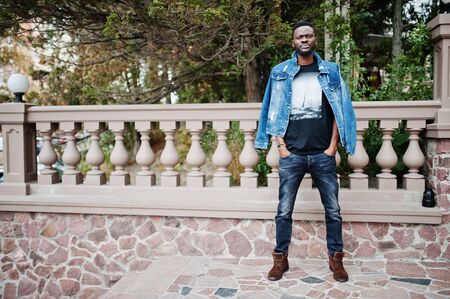 Young attractive serious african american man model. Modern handsome guy in jeans jacket standing on urban city street.の写真素材