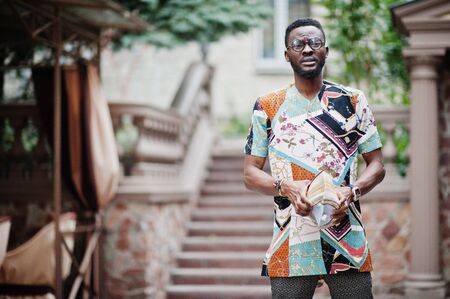 Handsome afro american man wearing traditional clothes, cap and eyeglasses in modern city.の写真素材