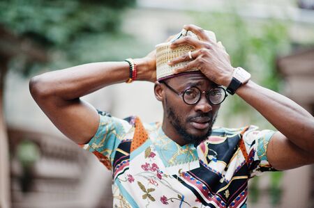 Handsome afro american man wearing traditional clothes, cap and eyeglasses in modern city.の写真素材