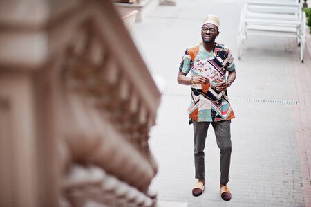 Handsome afro american man wearing traditional clothes, cap and eyeglasses in modern city.の写真素材