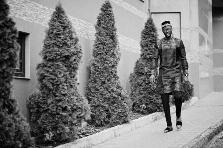 Handsome afro american man wearing traditional clothes, cap and eyeglasses in modern city.の写真素材