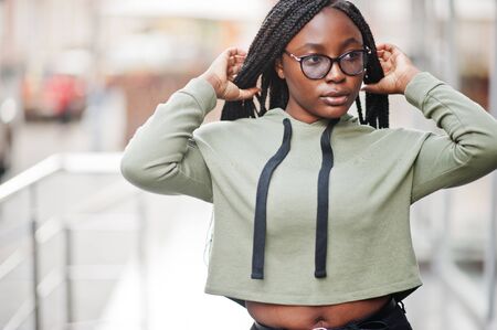 City portrait of positive young dark skinned female wearing green hoody and eyeglasses.の写真素材