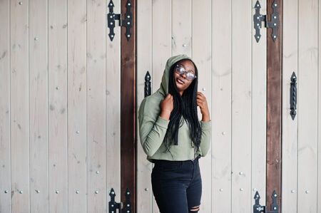 City portrait of positive young dark skinned female wearing green hoody and eyeglasses.の写真素材