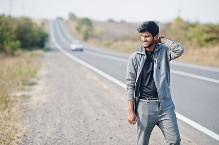 Hitchhiking indian man travelling by hitchhike on road side on highway.の写真素材