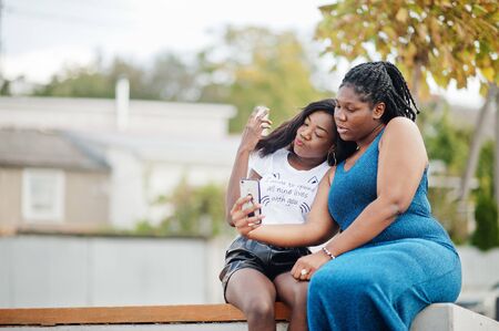 Two african american dark skinned friends female. One of them plus size model, second slim. Having...