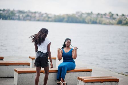Two african american dark skinned friends female. One of them plus size model, second slim. Having...