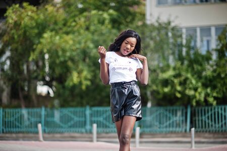 African american dark skinned slim model posed in a black leather shorts and white t-shirt.の写真素材
