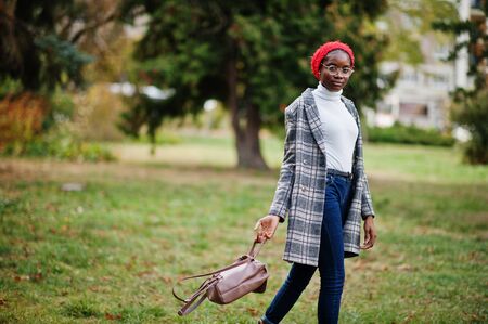 Young modern fashionable, attractive, tall and slim african muslim woman in hijab or turban head scarf and coat posed at park.の写真素材