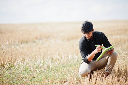 South asian agronomist farmer inspecting wheat field farm. Agriculture production concept.