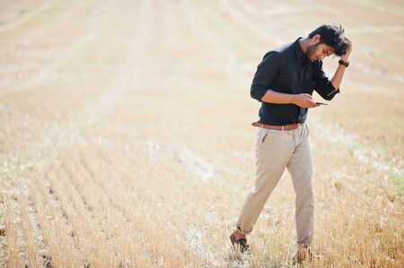 South asian agronomist farmer inspecting wheat field farm. Agriculture production concept.