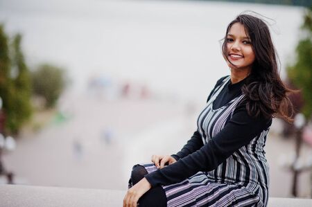 Portrait of young beautiful indian or south asian teenage girl in dress against river.