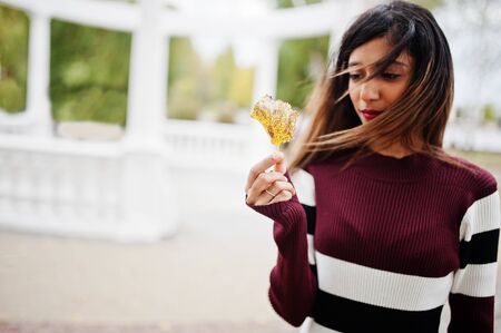 Portrait of young beautiful indian or south asian teenage girl in dress hold yellow leaves at hand.の写真素材