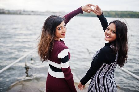 Portrait of back two young beautiful indian or south asian teenage girls in dress show  joined hands.の写真素材