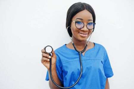 Portrait of happy female african american young doctor pediatrician in blue uniform coat and stethoscope isolated on white. Healthcare, medical, medicine specialist - concept.の写真素材