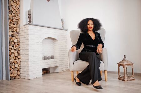 Stylish african american woman in black posed at room against fire place.の写真素材