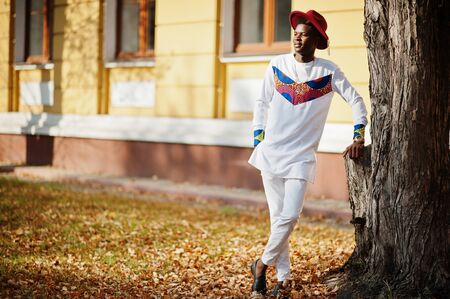 Stylish trendy afro france man in red hat and white outfit posed at autumn day. Black african model...