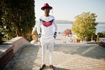 Stylish trendy afro france man in red hat and white outfit posed at autumn day. Black african model...