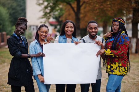 Group of five african college students on campus at university yard hold empty white blank. Free space for your text. Black afro friends studying.の写真素材