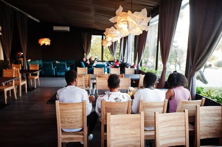 Happy african friends sitting, chatting in cafe and eat food. Group of black peoples meeting in...