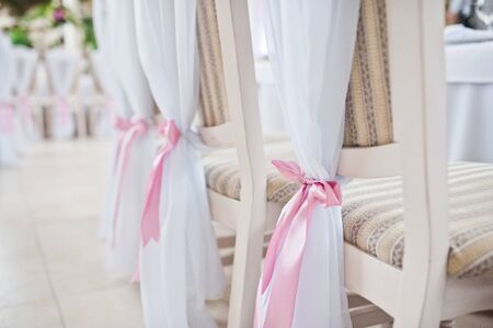Beautiful wedding set decoration in the restaurant. Pink ribbons on chairs.の写真素材