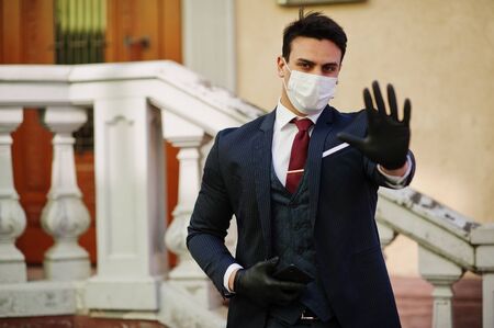 Concept of coronavirus quarantine. Business man wear on suit with medical face mask and mobile phone...