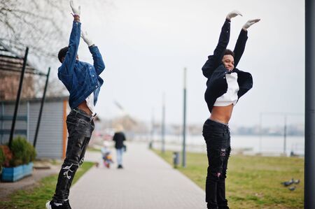 Two african teenagers friends at park wearing medical masks protect from infections and diseases...