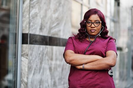 African american female doctor at red lab uniform with stethoscope. Medicine, profession and healthcare concept.の写真素材