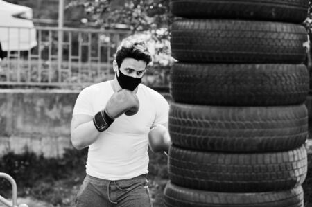 Portrait sports arabian boxer man in black medical face mask boxing outdoor during coronavirus quarantine.の写真素材