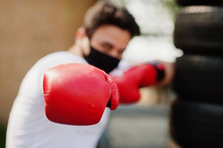 Portrait sports arabian boxer man in black medical face mask boxing outdoor during coronavirus quarantine.の写真素材