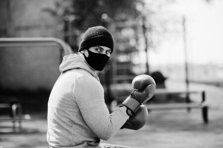 Portrait sports arabian boxer man in black medical face mask boxing outdoor during coronavirus quarantine.の写真素材