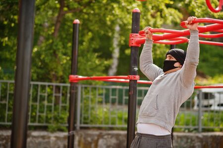 Portrait sports arabian man in black medical face mask doing workout exercises in outdoor gym place...