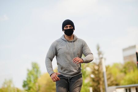 Portrait sports arabian man in black medical face mask run outdoor during coronavirus quarantine.