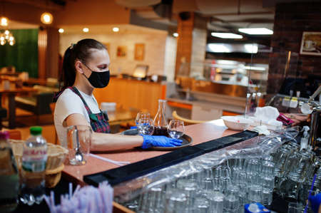 Waiter in protective mask hold tray with alcohol drink in the restaurant.の写真素材