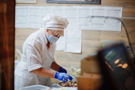Pizza maker in protective mask working in the pizzeria.の写真素材