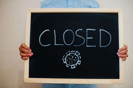 Closed. Coronavirus concept. Boy hold inscription on the board.の写真素材