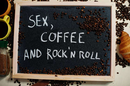 Sex, coffee and rock n roll. Words on blackboard flat lay.