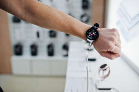Seller man mobile phone professional consultant in tech store or shop check new smart watches.