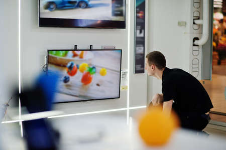 Seller man professional consultant in tech store or shop stand near smart TV.