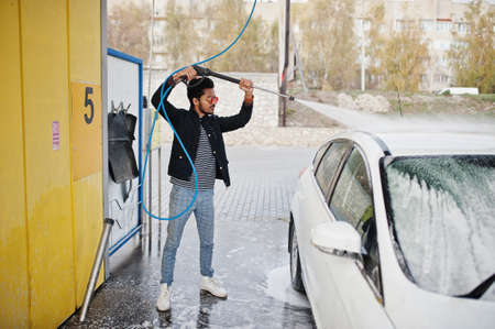 South asian man or indian male washing his white transportation on car wash.の写真素材