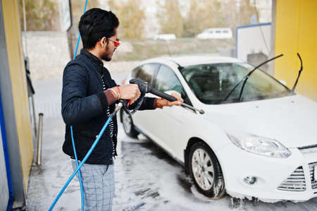 South asian man or indian male washing his white transportation on car wash.の写真素材