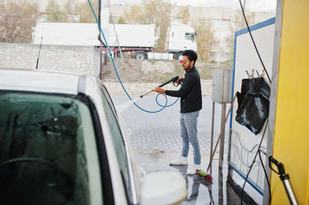 South asian man or indian male washing his white transportation on car wash.