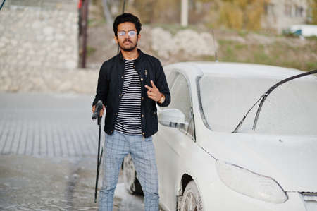South asian man or indian male washing his white transportation on car wash.